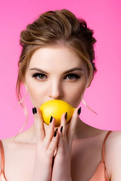 Elegante hermosa mujer rubia sosteniendo limón maduro aislado en rosa - foto de stock
