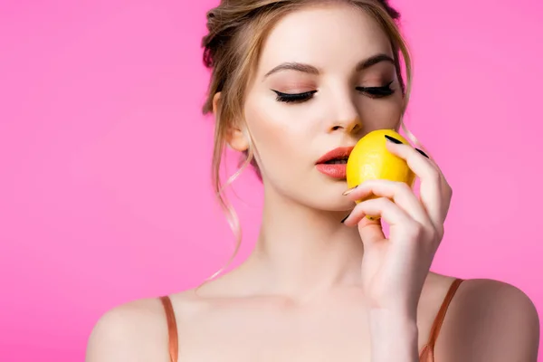 Elegant beautiful blonde woman holding ripe lemon near lips isolated on pink — Stock Photo