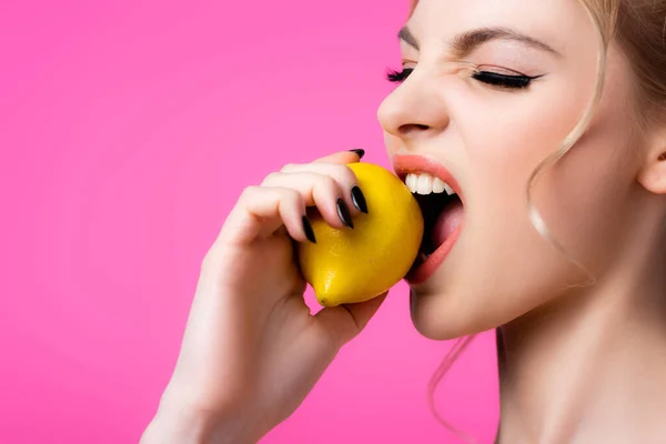 Bela mulher loira mordendo limão maduro isolado em rosa — Fotografia de Stock