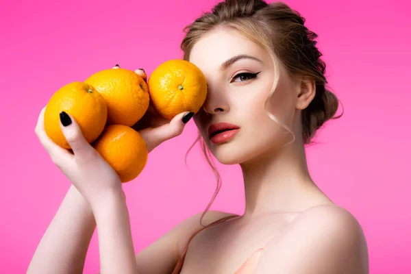 Elegant beautiful blonde woman holding ripe oranges isolated on pink — Stock Photo