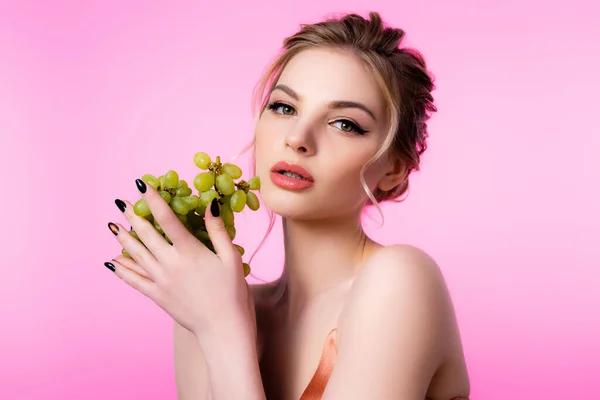 Елегантна красива блондинка тримає зелений виноград ізольовано на рожевому — стокове фото