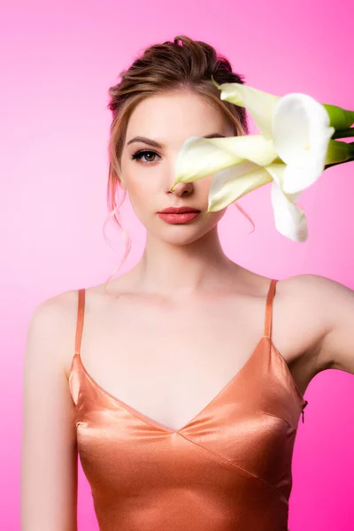 Elegant beautiful blonde woman holding calla flowers in front of face isolated on pink — Stock Photo