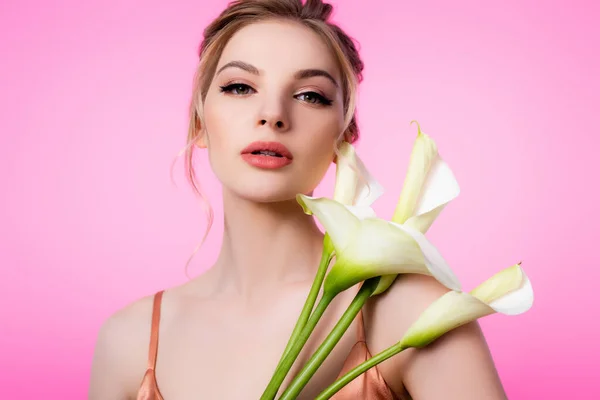 Elegante hermosa mujer rubia sosteniendo flores de calla aisladas en rosa - foto de stock