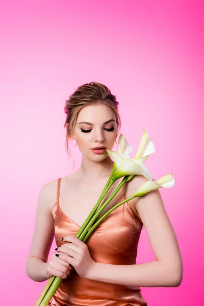 Elegante hermosa mujer rubia sosteniendo flores de calla aisladas en rosa - foto de stock