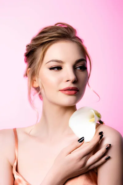 Élégante belle femme blonde tenant fleur de calla sur l'épaule isolée sur rose — Photo de stock