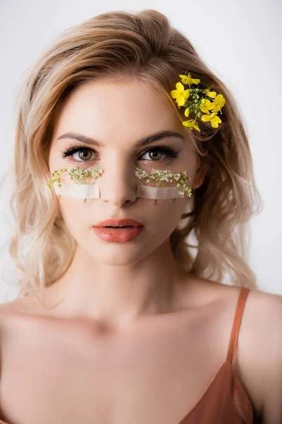 Belle femme blonde avec des fleurs sauvages sous les yeux isolés sur blanc — Photo de stock