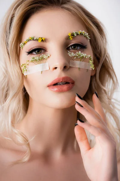 Naked beautiful blonde woman in silk dress with wildflowers under eyes isolated on white — Stock Photo