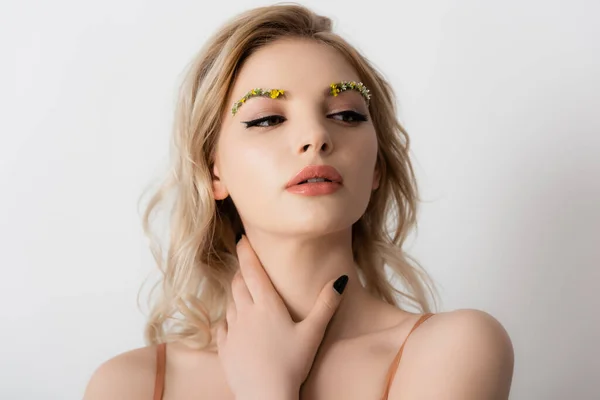 Schöne blonde Frau mit Wildblumen auf den Augenbrauen berühren Hals isoliert auf weiß — Stockfoto