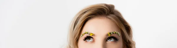 Vue recadrée de belle femme blonde avec des fleurs sauvages sur les sourcils regardant vers le haut isolé sur blanc regardant loin — Photo de stock