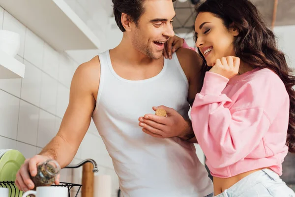 Focus selettivo della donna allegra che abbraccia il fidanzato versando il tè in tazza in cucina — Foto stock