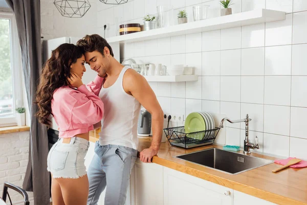 Belle femme sexy étreignant petit ami souriant dans la cuisine — Photo de stock