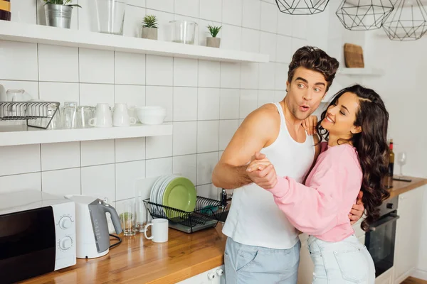 Handsome man dancing with beautiful smiling woman in kitchen — Stock Photo