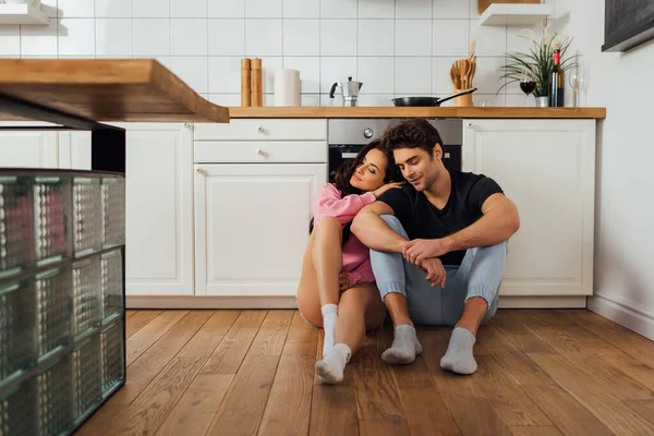 Focus selettivo di bella donna abbracciando fidanzato con gli occhi chiusi sul pavimento della cucina — Foto stock