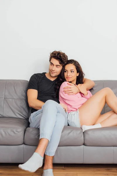 Enfoque selectivo del hombre guapo abrazando hermosa novia en el sofá en casa - foto de stock