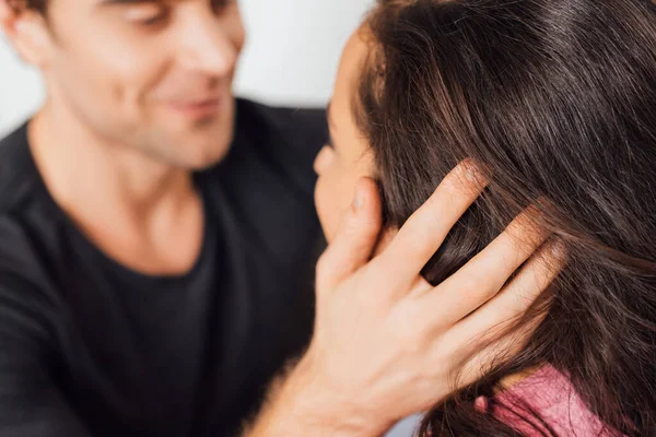 Focus selettivo dell'uomo toccando i capelli della ragazza isolata sul grigio — Foto stock