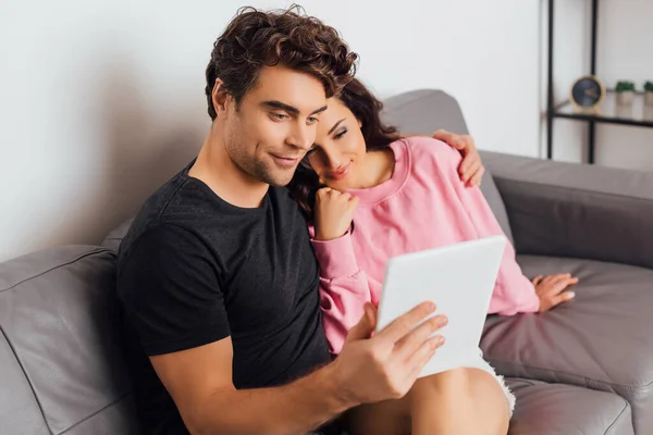 Selective focus of young couple using digital tablet in living room — Stock Photo