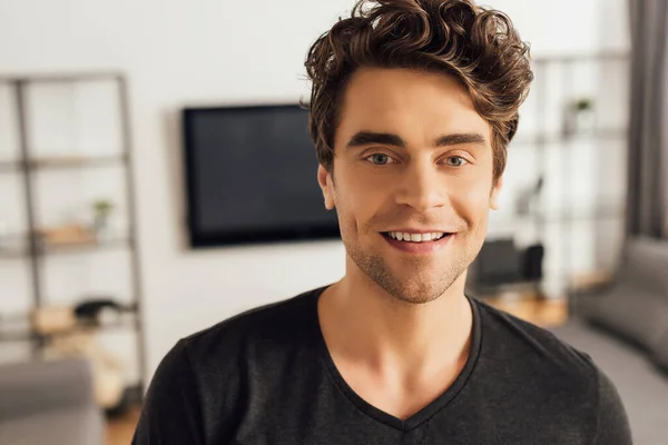 Beau homme souriant à la caméra dans le salon — Photo de stock