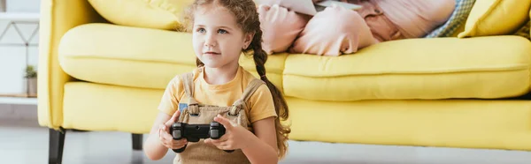 KYIV, UKRAINE - JUNE 19, 2020: cropped view of nanny on sofa and kid playing video game with joystick, horizontal image — Stock Photo