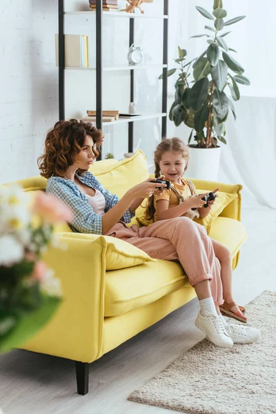 KYIV, UKRAINE - 19 JUIN 2020 : mise au point sélective de la jeune baby-sitter et mignon enfant jouer à un jeu vidéo — Photo de stock