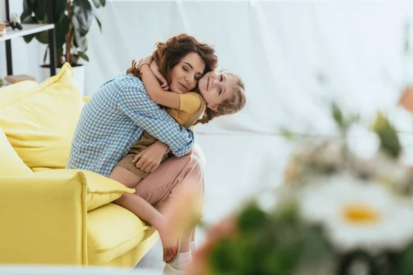 Foco seletivo de babá feliz e criança abraçando enquanto sentado no sofá — Fotografia de Stock