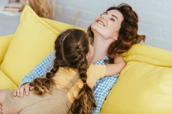 Ребенок обнимает счастливую няню, сидя на диване с закрытыми глазами — стоковое фото