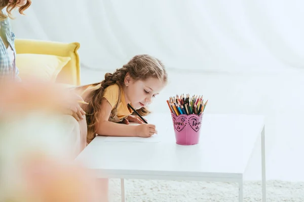 Abgeschnittene Ansicht des Babysitters in der Nähe entzückender Kinderzeichnung mit Bleistift, selektiver Fokus — Stockfoto