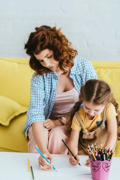 Attractive babysitter and adorable child drawing with pencils together — Stock Photo