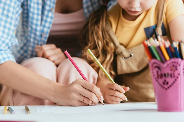 Vue partielle de baby-sitter et dessin d'enfant avec crayons ensemble — Photo de stock