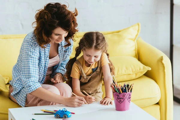 Junge Babysitterin und entzückendes Kind zeichnen mit Bleistiften zusammen — Stockfoto