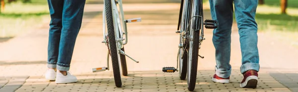 Panoramic crop of senior coupe walking near bicycles on urban street — Stock Photo