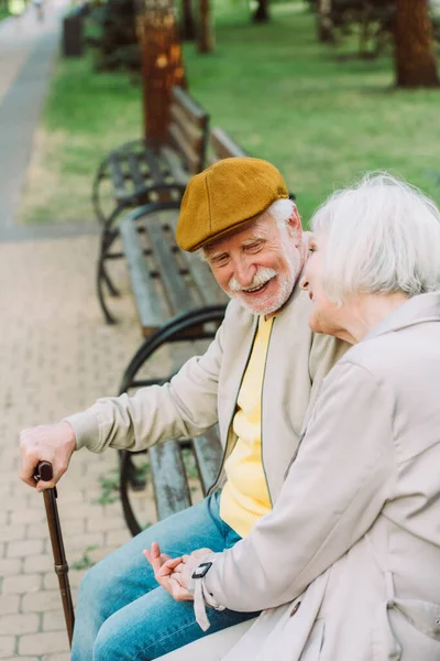 Selective focus of smiling senior man looking at wife on bench in park — Stock Photo