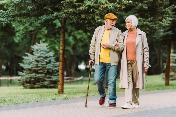 Senior couple smiling while walking on path in park — Stock Photo