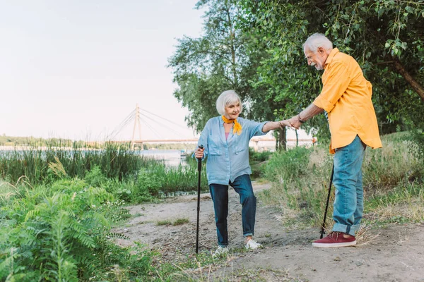 Lächelnder Senior hilft Frau mit Gehstock auf Weg im Park — Stockfoto