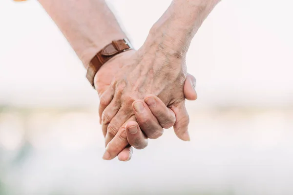 Cropped view of senior couple holding hands — Stock Photo