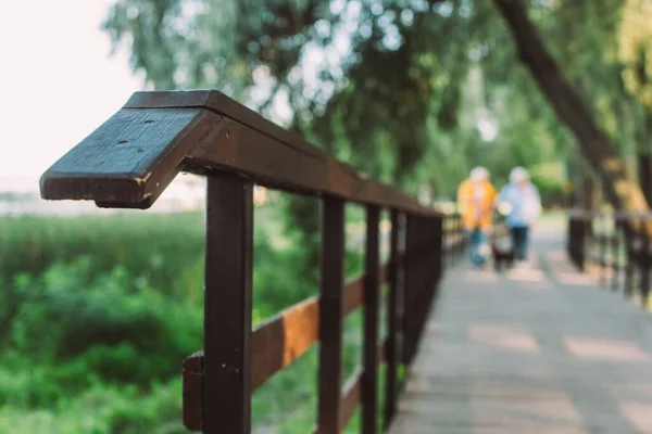 Selective focus of wooden bridge and couple walking in park — Stock Photo