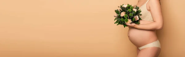 Partial view of young pregnant woman in underwear holding bouquet of fresh flowers on beige, panoramic shot — Stock Photo