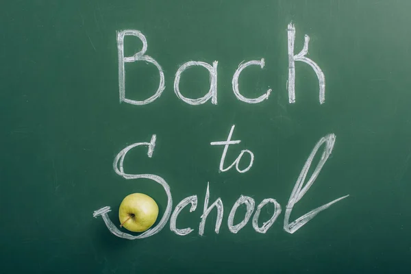 Top view of ripe apple near back to school lettering on green chalkboard — Stock Photo