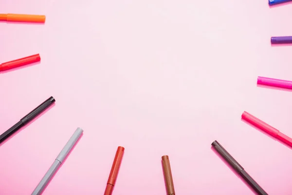 Cornice di pennarelli a colori su sfondo rosa con spazio copia, vista dall'alto — Foto stock