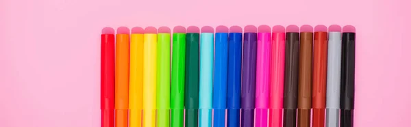 Panoramic shot of color felt-tip pens row on pink background, top view — Stock Photo