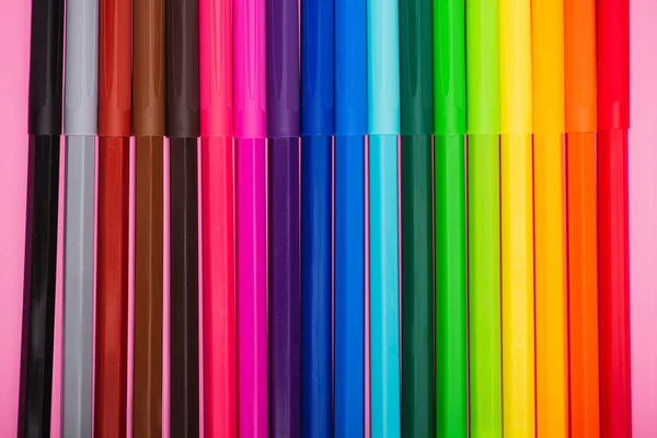 Vue du haut de la rangée de stylos feutre multicolores sur fond rose — Photo de stock