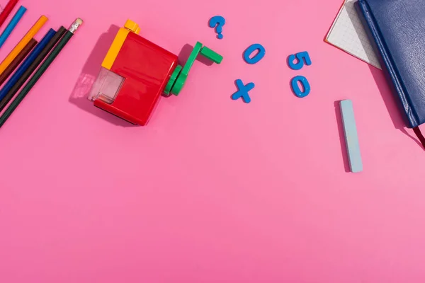 Vista dall'alto di temperamatite, matite di colore, notebook, pastello, magneti e matite di colore su rosa — Foto stock