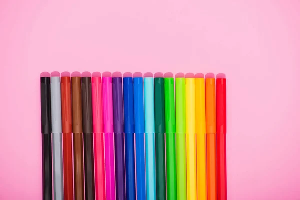 Vista superior de plumas de fieltro multicolores colocadas sobre fondo rosa con espacio para copiar - foto de stock