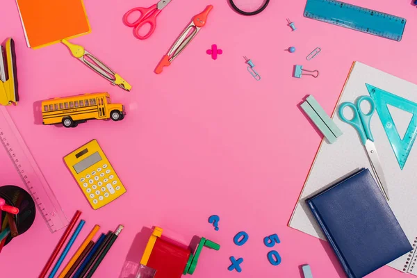 Top view of school supplies and school bus model on pink with copy space — Stock Photo