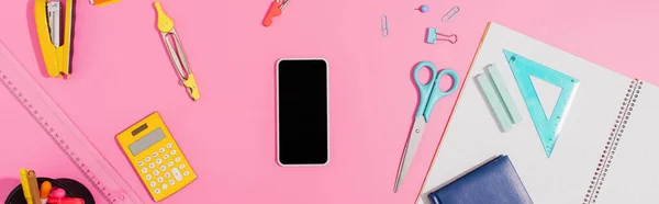 Top view of smartphone with blank screen near school stationery on pink, horizontal concept — Stock Photo