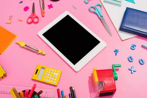 Vue grand angle de la tablette numérique près des ordinateurs portables et fournitures scolaires sur rose — Photo de stock