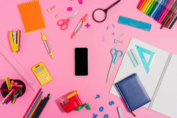 Ansicht des Smartphones mit leerem Bildschirm, umgeben von Schulmaterialien auf rosa — Stockfoto