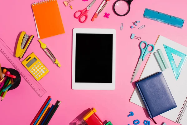 Vue du dessus de la tablette numérique avec écran blanc près des fournitures scolaires sur rose — Photo de stock