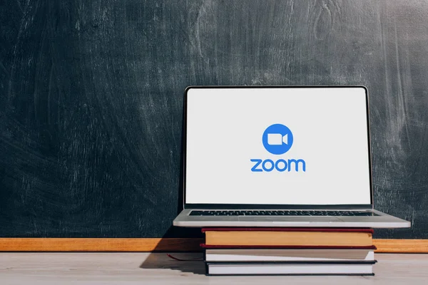 KYIV, UKRAINE - JULY 7, 2020: Laptop with Zoom website on stacked textbooks near black chalkboard — Stock Photo