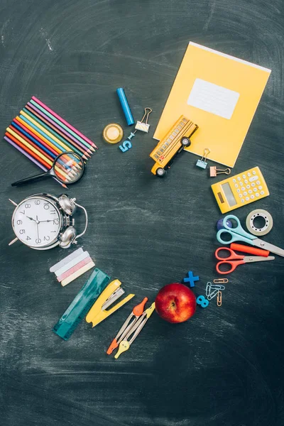 Top view of frame with vintage alarm clock, whole apple and school supplies on black chalkboard with copy space — Stock Photo