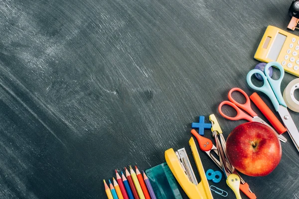 Vue de dessus de la pomme mûre et de la papeterie scolaire sur un tableau noir avec espace de copie — Photo de stock